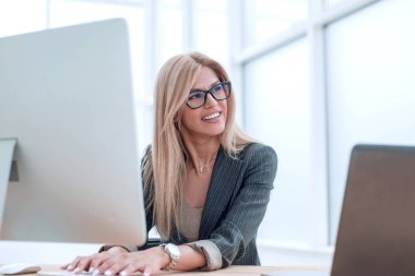 Genç iş kadını aynı anda hem bilgisayar hem de laptop kullanıyor.