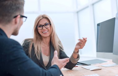 İş arkadaşları bilgisayar masasında oturan iş görevlerini tartışıyor