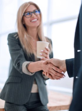 Bir fincan kahveli genç iş kadını meslektaşına hoş geldin diyor.