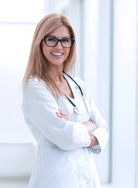 Usmívající se doktorka stojí u okna nemocnice — Stock fotografie