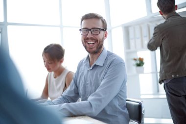 Kapat. Ofis masasında oturan başarılı bir iş adamı.