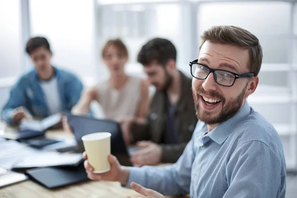 Rückansicht. Geschäftsmann mit einer Tasse Kaffee und Blick in die Kamera — Stockfoto