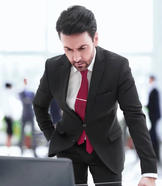 Affärsman står vid sitt skrivbord och tittar på den bärbara skärmen — Stockfoto