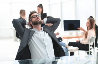 Düşünceli genç işadamı ofis masasında oturuyor.