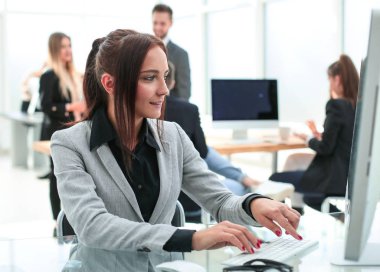 Modern bir ofiste bilgisayarda çalışan genç bir kadın.