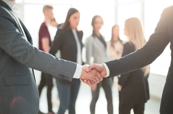 De cerca. fuerte apretón de manos de la gente de negocios en el fondo de la oficina. — Foto de Stock