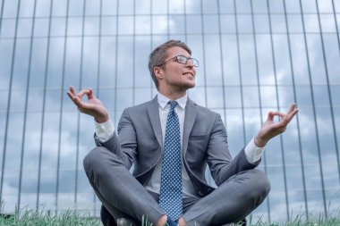 Lotus 'taki işadamı ofis binasının önündeki çimlere oturmuş poz veriyor