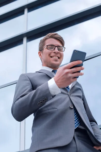 Leende affärsman läser Sms på sin smartphone — Stockfoto