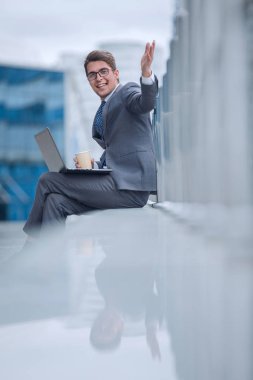 Gülümseyen iş adamı dizüstü bilgisayarı ve kahvesi olan.