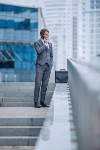 Homme d'affaires parlant sur smartphone tout en se tenant debout sur les marches à l'extérieur — Photo