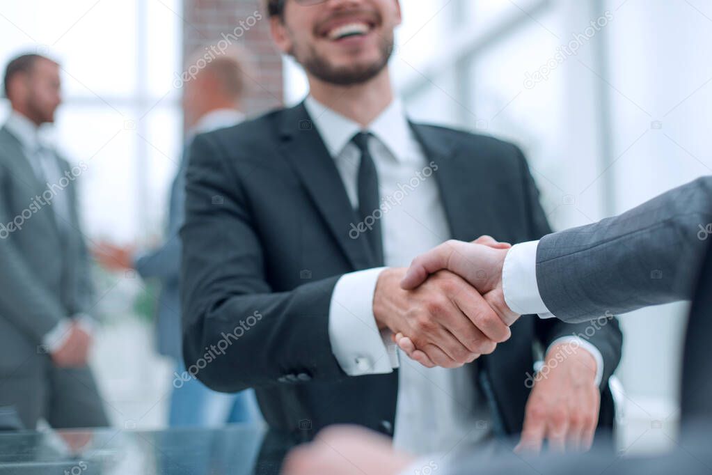 happy business partners shaking hands at the negotiating table.