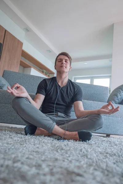 Casual guy sitting in Lotus position on carpet in his living room — 스톡 사진