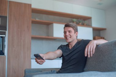 Kapat. Genç adam televizyon izlemek için akıllı telefonunu kullanıyor.