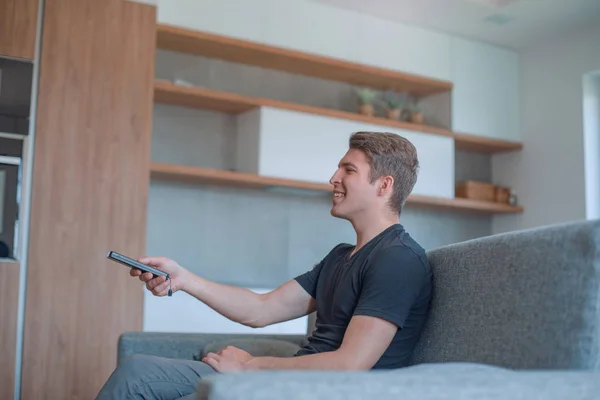 De cerca. hombre joven encendiendo la televisión usando su teléfono inteligente — Foto de Stock