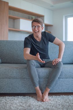 Oturma odasındaki koltukta oturan başarılı genç adam.