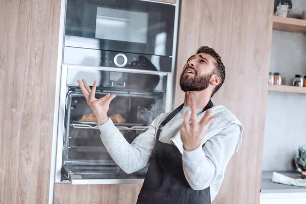 Sorprendido hombre de pie cerca del horno con croissants quemados. — Foto de Stock