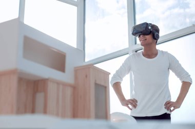 Gülümseyen iç mimar masasının önünde duruyor.