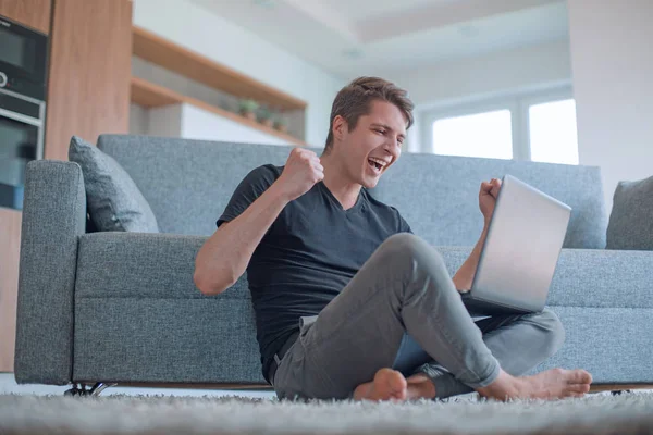 Hombre alegre viendo un video sentado en el suelo en la sala de estar —  Fotos de Stock