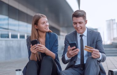 Banka kartını kullanan gençler ofis binasının yanında oturuyorlar