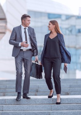 Genç çalışanlar konuşuyor, iş merkezine giderken birlikte yürüyorlar.