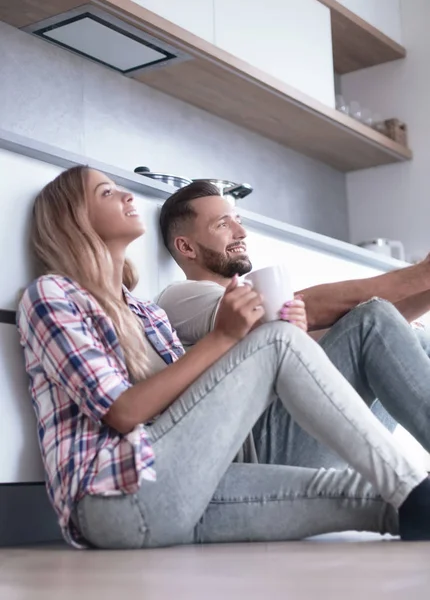 Pareja joven tomando café sentado en el suelo de la cocina —  Fotos de Stock