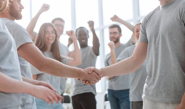 Handdruk van jongeren op de achtergrond van het jubelende team — Stockfoto