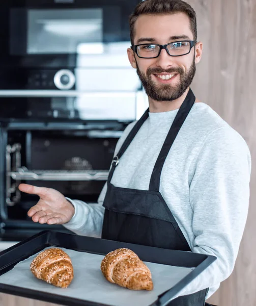 Sorrindo homem segurando uma bandeja de croissants frescos — Fotografia de Stock
