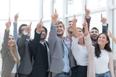 Bir grup mutlu genç iş adamı yukarıyı gösteriyor.