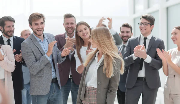 Счастливая молодая женщина стоит перед своими ликующими коллегами — стоковое фото