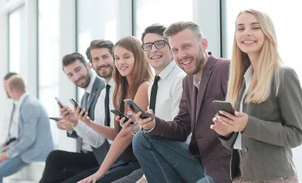 Gruppe junger Mitarbeiter sitzt im Büroflur. — Stockfoto