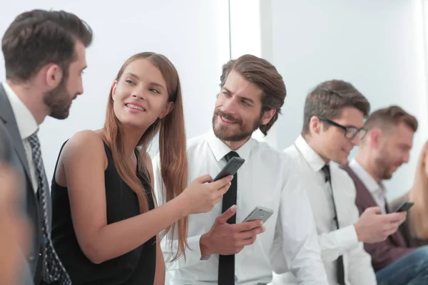 Jóvenes empleados de la empresa mirando las pantallas de sus teléfonos inteligentes —  Fotos de Stock