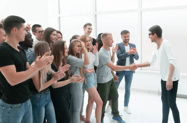 Jovens apertando as mãos, de pé entre seus amigos — Fotografia de Stock