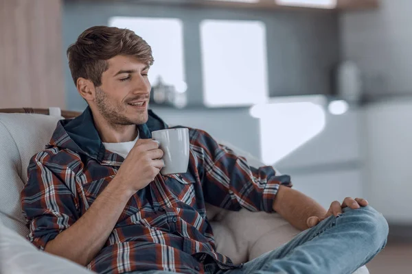 Ung man med en kopp kaffe i bakgrunden i köket — Stockfoto