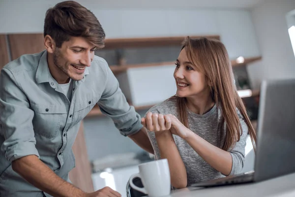 Linda pareja usando el ordenador portátil juntos en casa en la cocina — Foto de Stock