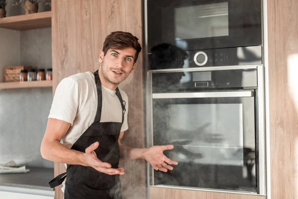 Frustrado joven de pie cerca del horno roto — Foto de Stock