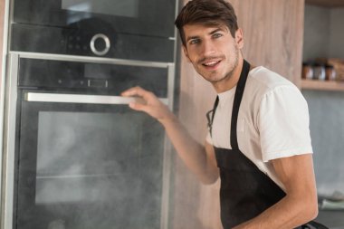 Duygusal genç adam kırık fırının yanında duruyor.