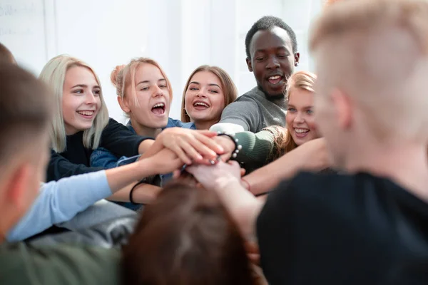 Nahaufnahme. eine Gruppe junger Leute verbindet ihre Handflächen zu einem Haufen — Stockfoto