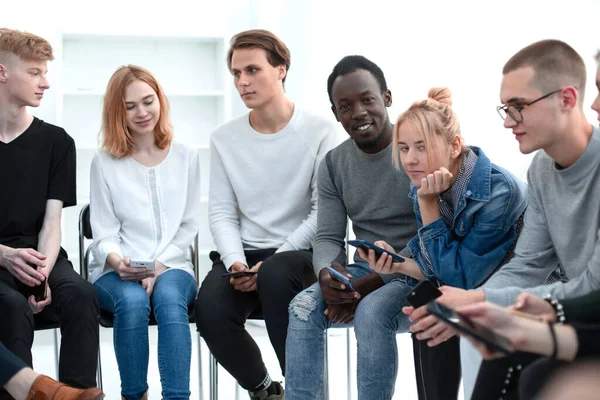 Diversos jovens usam seus smartphones sentados na fila — Fotografia de Stock