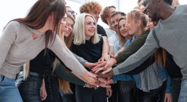 Çeşitli gençler ellerini birleştiriyor.