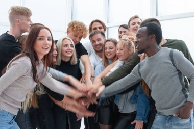 Çeşitli gençler ellerini birleştiriyor.