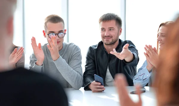 Grupo de jóvenes aplaudiendo sentarse en una mesa redonda . —  Fotos de Stock