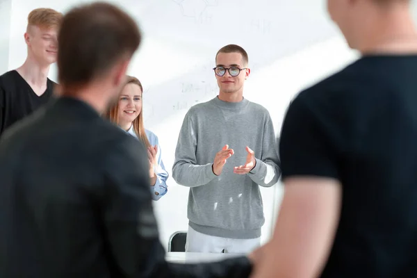 Gruppe unterschiedlicher junger Leute steht um einen runden Tisch — Stockfoto