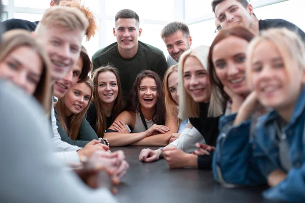 Muitos jovens diversos sentados à mesma mesa — Fotografia de Stock