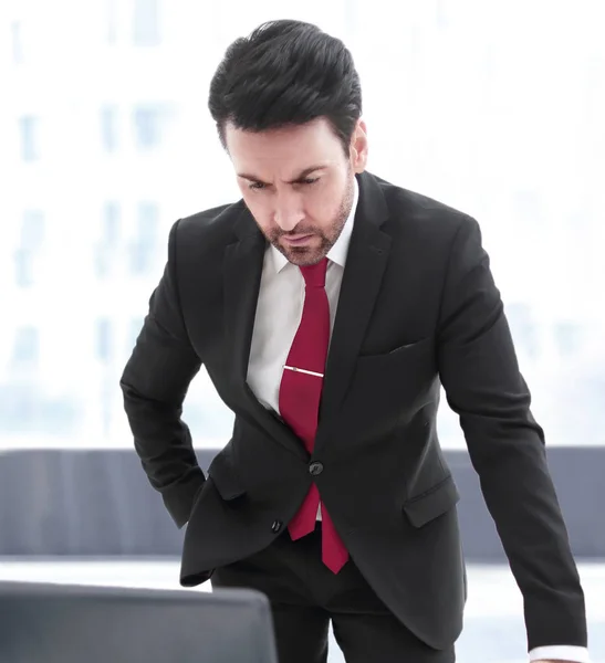 Affärsman står vid sitt skrivbord och tittar på den bärbara skärmen — Stockfoto