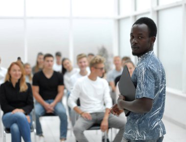 Genç adam iş kursunun öğrencilerinin önünde duruyor.