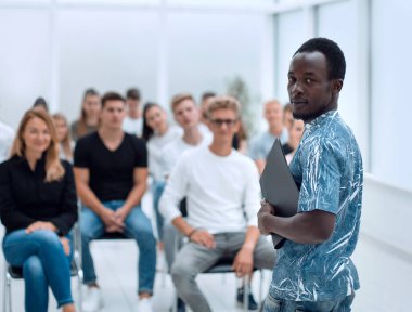 Genç adam iş kursunun öğrencilerinin önünde duruyor.