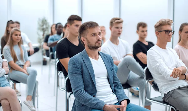 Lässiger junger Mann sitzt inmitten der Seminarteilnehmer — Stockfoto