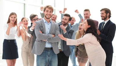 Meslektaşlarının arasında duran mutlu genç iş adamı.