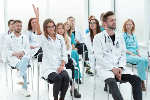 Женщина-врач задает вопрос преподавателю во время семинара — стоковое фото