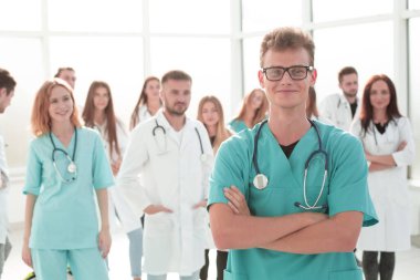 Gülümseyen genç doktor kıdemli meslektaşlarının önünde duruyor..